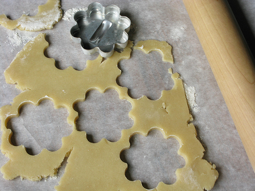 A close up view of a flattened dough with flower shaped cutouts.
