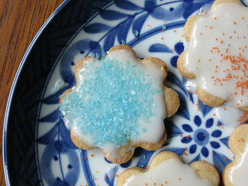 Frosted flower power cookies served on a blue and white plate.