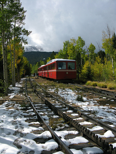 Image of a red train on an old railroad track on a beautiful sunny day.