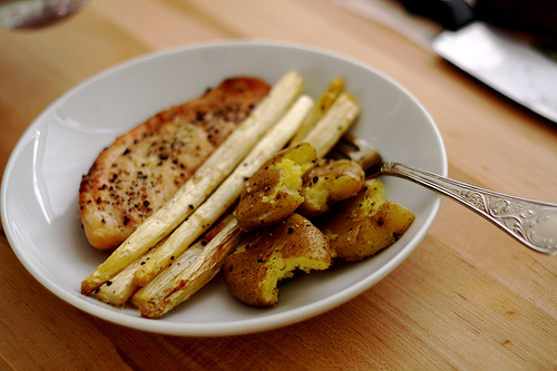 A plate of baked tilapia with white asparagus and baby potatoes.