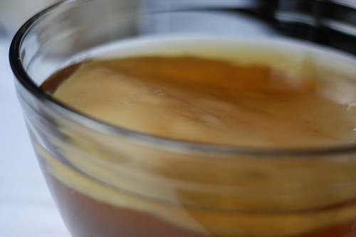 A glass bowl filled with kombucha mixture in the process of fermentation.