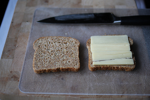 An image of pieces of bread with one filled with thin slices of cheese.