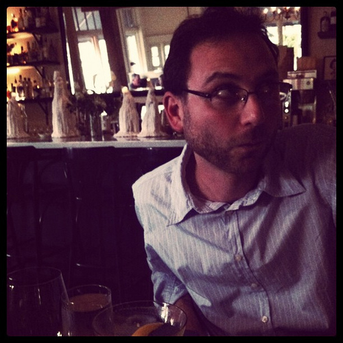 An image of a man with glasses inside a restaurant. 