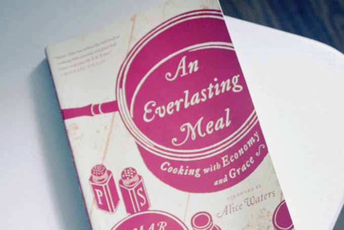 A copy of the An Everlasting Meal Cookbook on a white table.