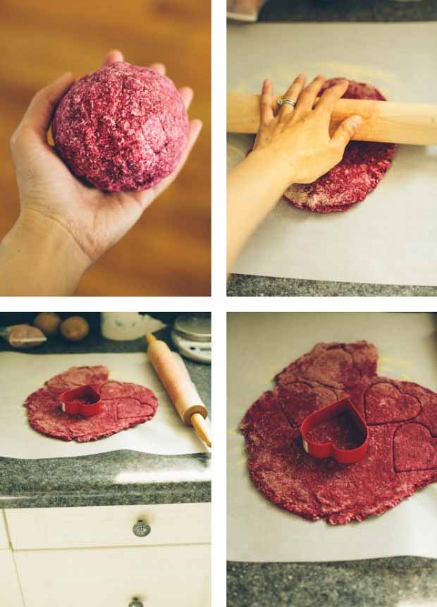 A collage of four overhead images: a hand holding a ball of red dough, a hand using a rolling pin to roll out dough on a piece of white parchment paper, rolled dough on parchment on a kitchen counter with a rolling pin to the right and heat-shaped cookie cutter on top, and closeup overhead image of a heart-shaped cookie cutter on top of the round of rolled dough.