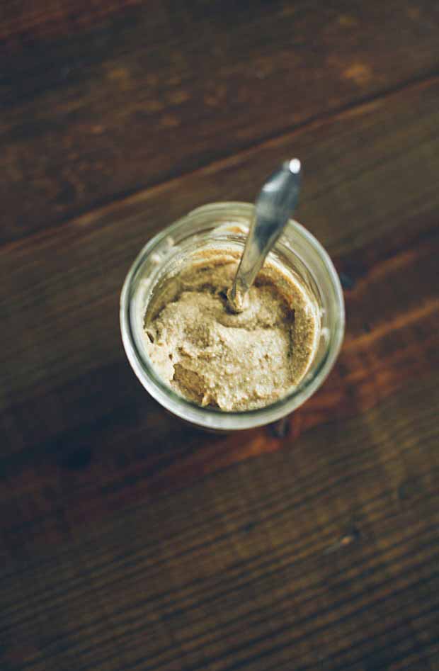 Top down of a mason jar full of soaked vanilla maple almond butter on a dark wooden background.