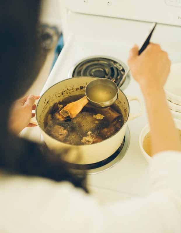 The author stirs perpetual beef bone broth in a cast iron Dutch oven.