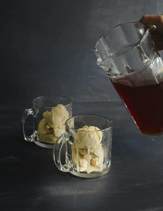 Motion picture of a glass pitcher of hot rooibos tea being poured over two clear glasses of vanilla ice cream | Foodal