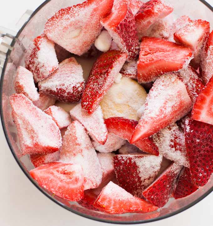 Top down view of fresh strawberry chunks in a food processor.