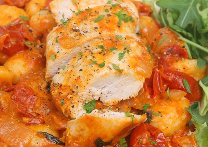 Horizontal close-up image of chicken cacciatore garnished with chopped fresh herbs.