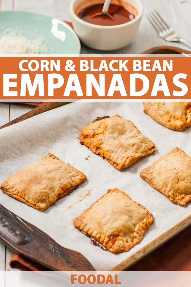 A batch of corn and black bean empanadas on a baking tray.