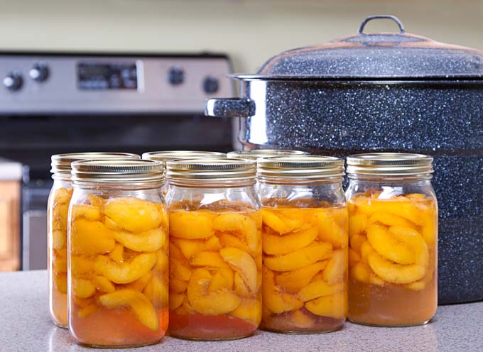 Canned Peaches with a water bath canner on counter.