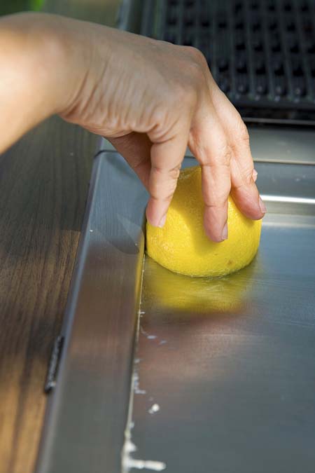 lemon being used on a stainless steel pan to remove stains