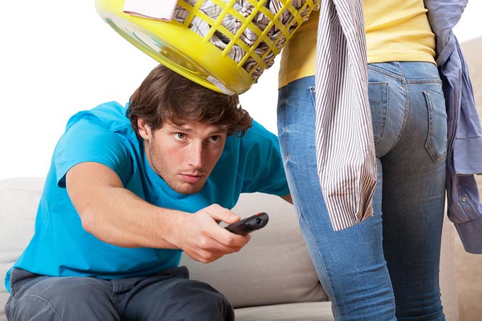 Man attempts to watch TV as woman tries to get him to help fold laundry