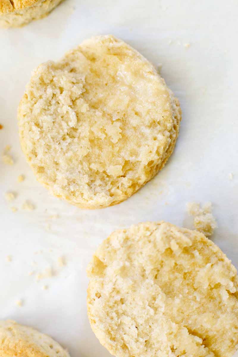 Closeup of halved vegan baked goods made with oat and wheat flour, showing the moist crumb inside, on a white background.