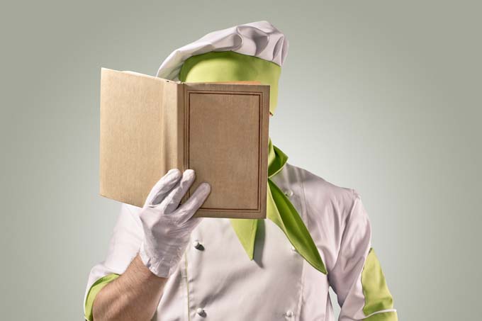 A cook examines a book containing cooking terms, lingo, and definitions.