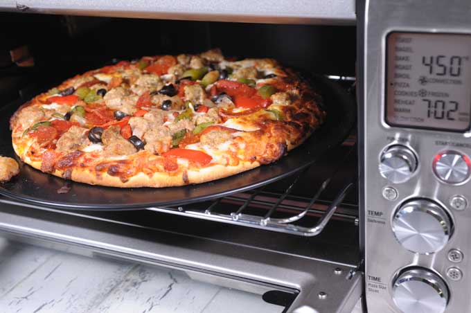 Oblique view of a Breville Smart Oven Pro baking pizza with the door open.