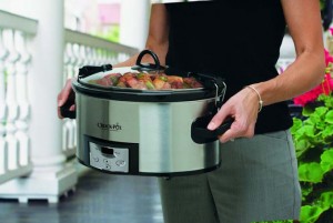Crock-Pot SCCPVL610-S Programmable Cook and Carry Oval Slow Cooker by carried by female in black shirt and grey pants. Shows only torso and hands of woman with detail being centered on the crock pot.