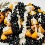 Close up of a roasted butternut squash with black rice and hemp seed and miso dressing.
