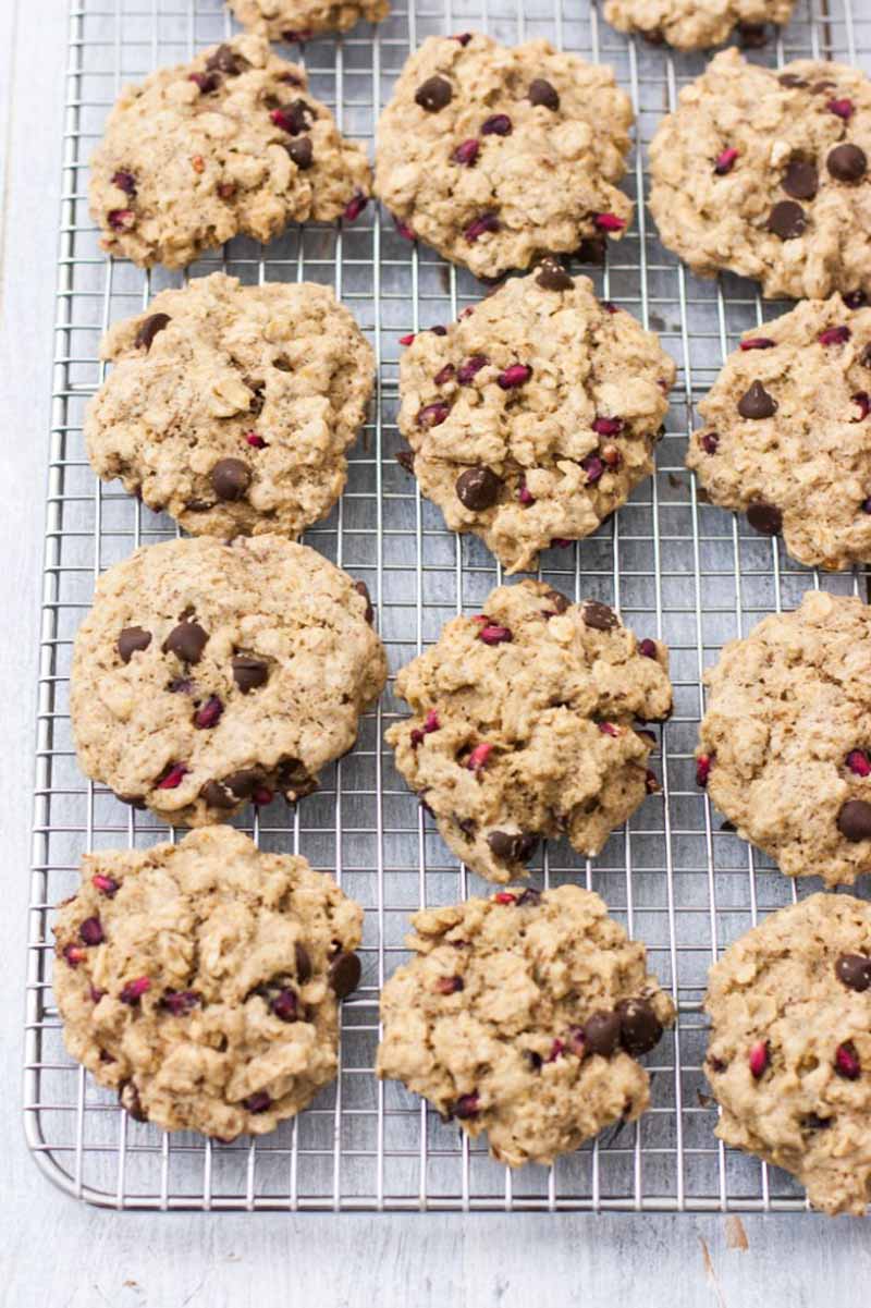 A top down view of a batch of vegan and gluten-free Chocolate & Pomegranate Oatmeal Cookies on a cooling rack.