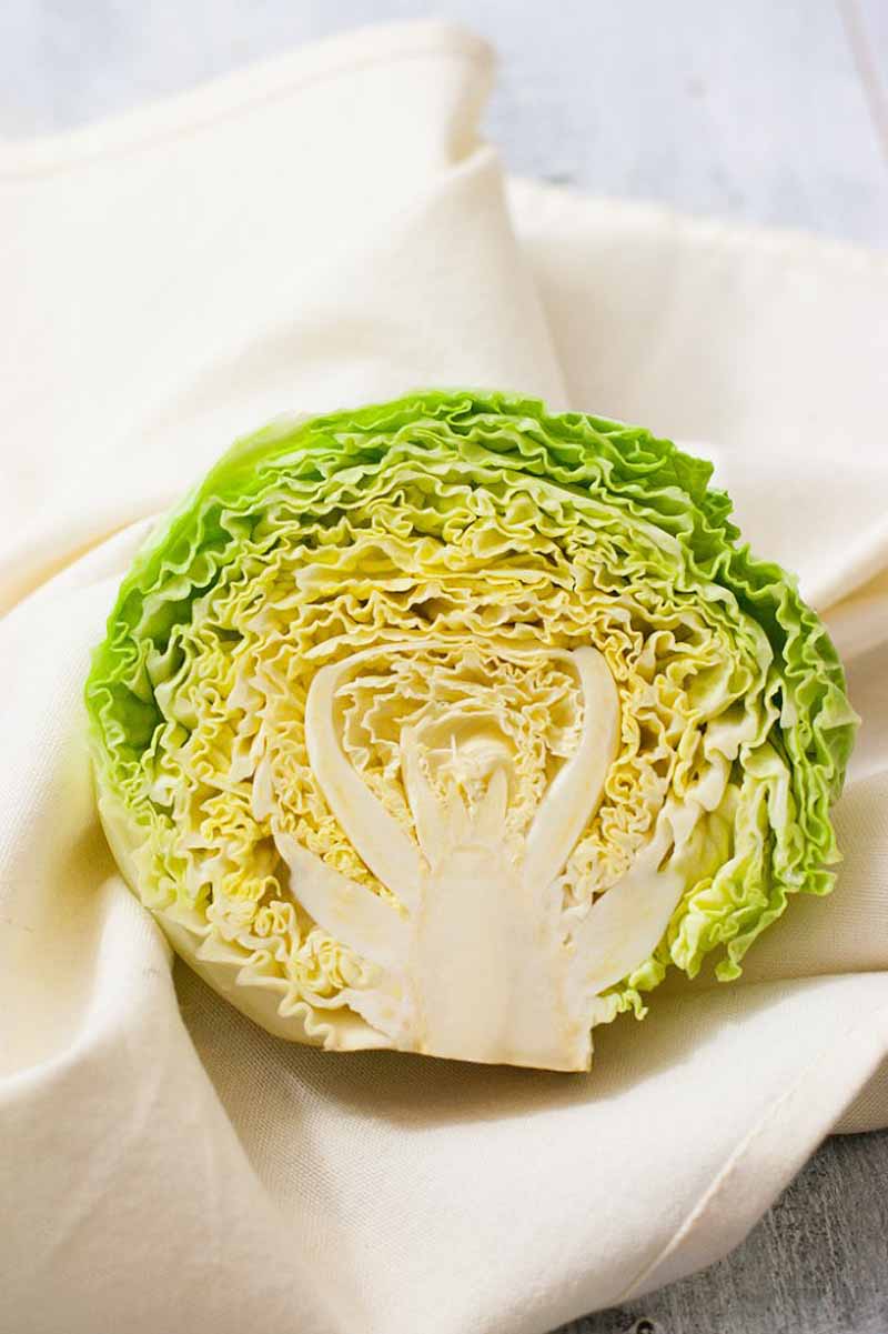 Half of a head of cabbage sitting in a wadded up white linen table cloth.