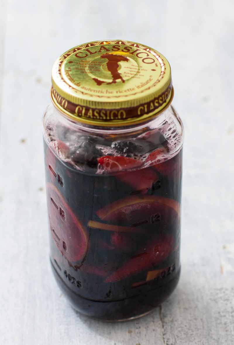 A mason jar with a lid on sealing in a red wine and mixed fresh fruit for soaking.