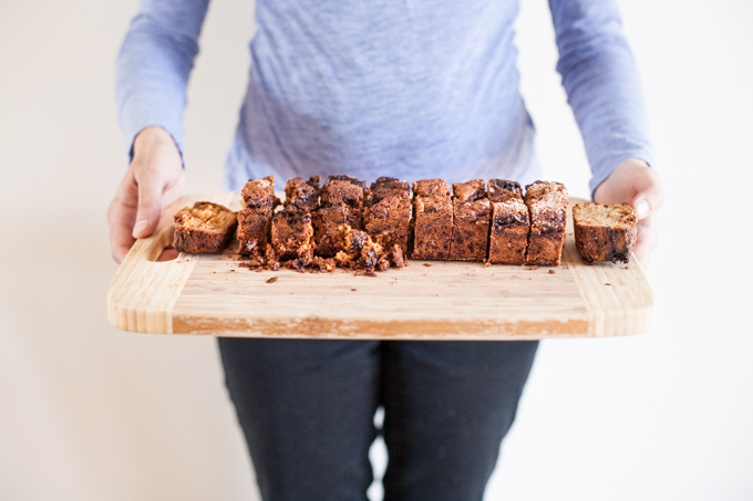 A woman holds a wooden cutting board with a ginger pear coffee cake with streusel topping | Foodal
