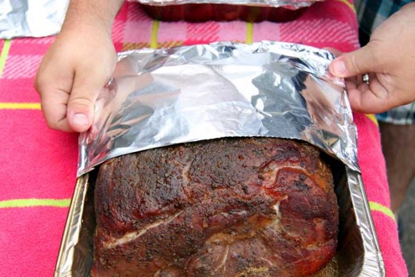 Wrapping smoked pulled pork with aluminum foil.