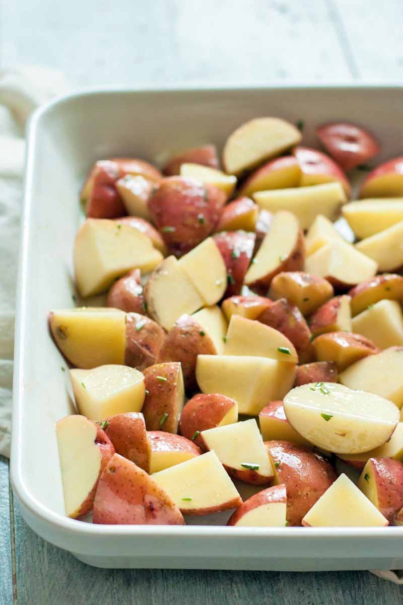 Sliced red-skinned potatoes in a ceramic baking dish.