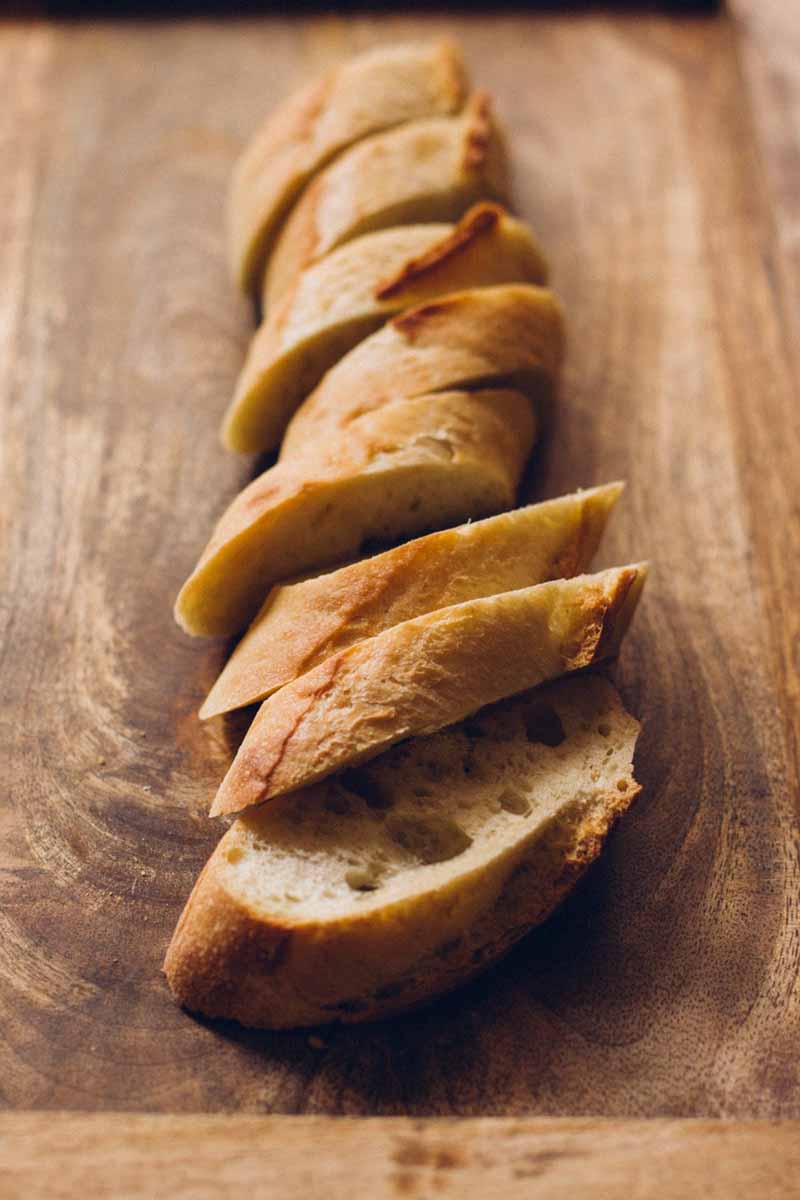 A complete baguette sliced into pieces from a bread knife.