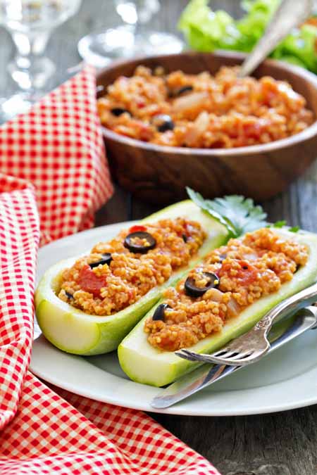 Recipe for vegan stuffed zucchini made with millet, tomatoes, and olives