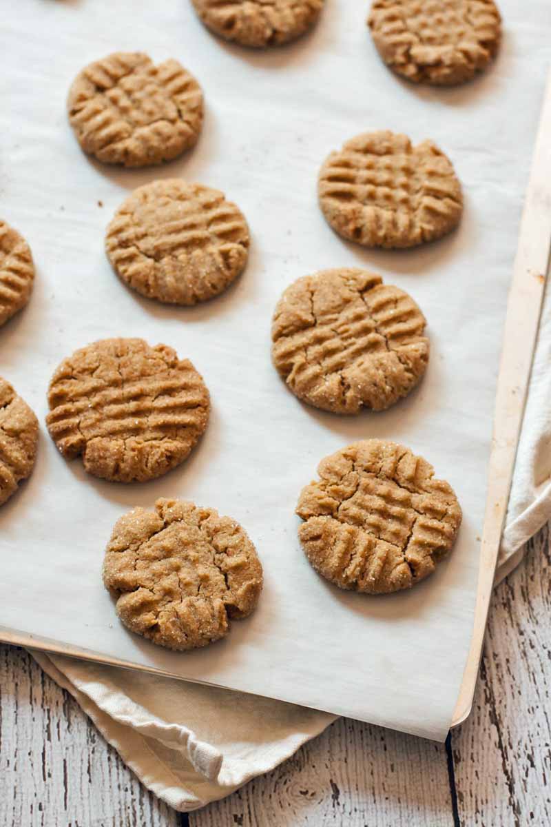 Top view of a batch of vegan peanut butter cookies on a baking sheet