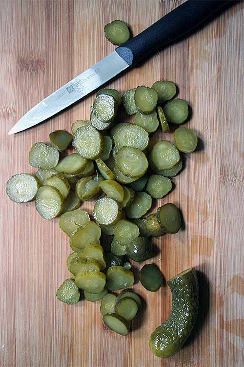 Sweet gherkin pickles on top of a wooden cutting board.