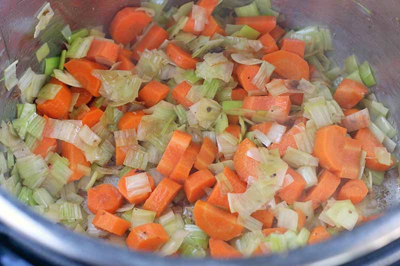 Leeks and carrots in a metal pressure cooker insert.
