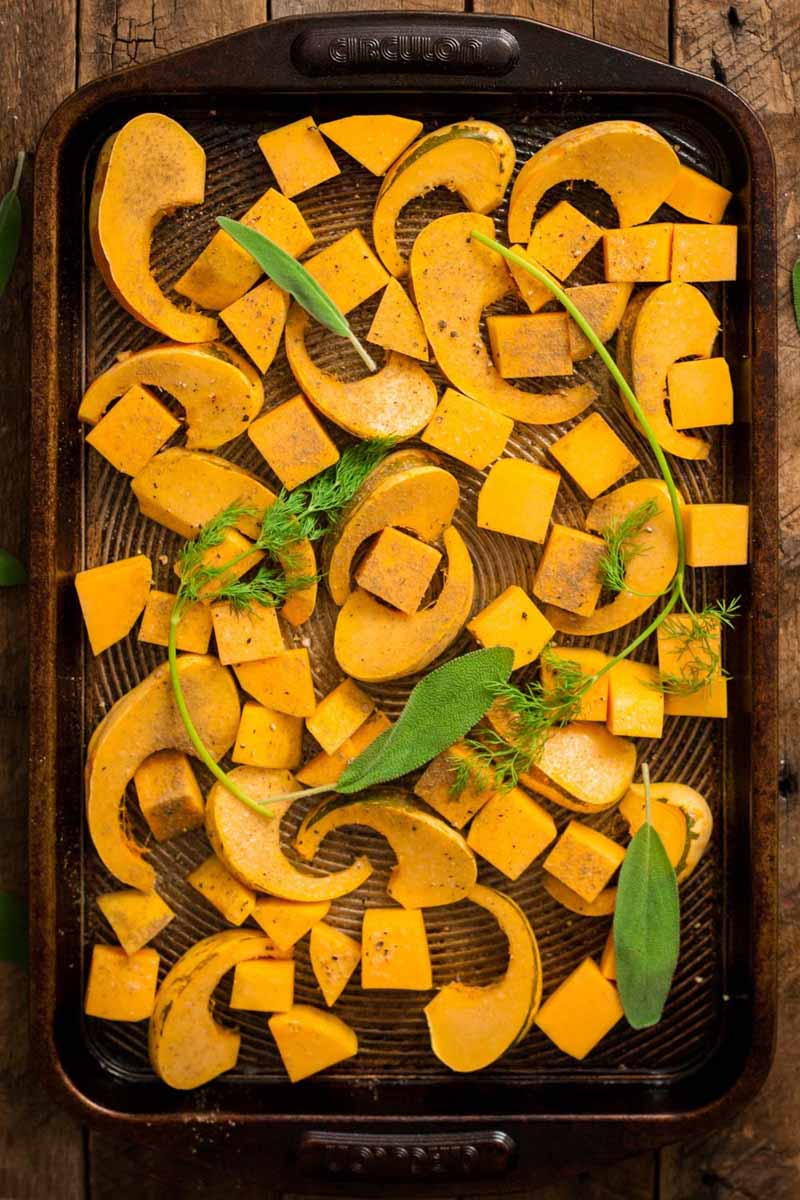 Top-down view of sliced, roasted butternut and sweet dumpling squash on a blackened baking sheet.