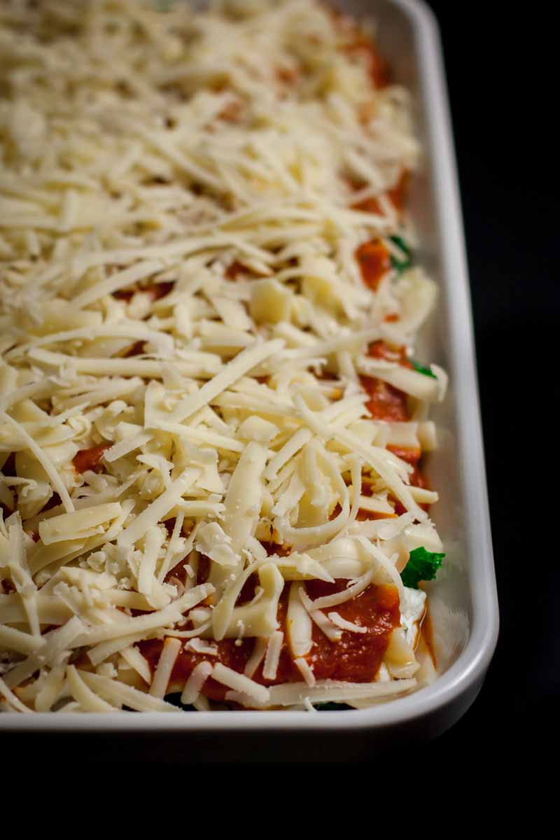 Top down view of a unbaked vegetarian lasagna in a white porcelain casserole dish. Close up view.