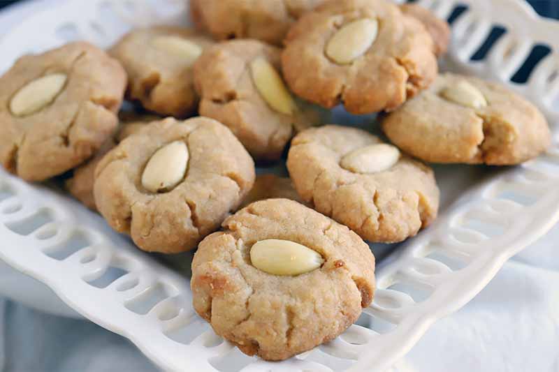 Brown butter almond cookies on a white decorative ceramic serving dish.
