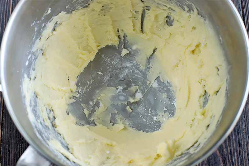 Creamed butter in a large stainless steel stand mixer bowl.