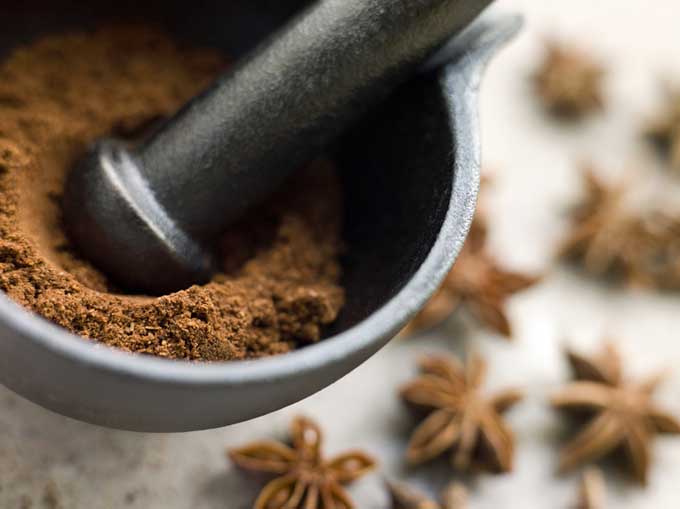 Star anise being ground in mortar and pestle | Foodal.com