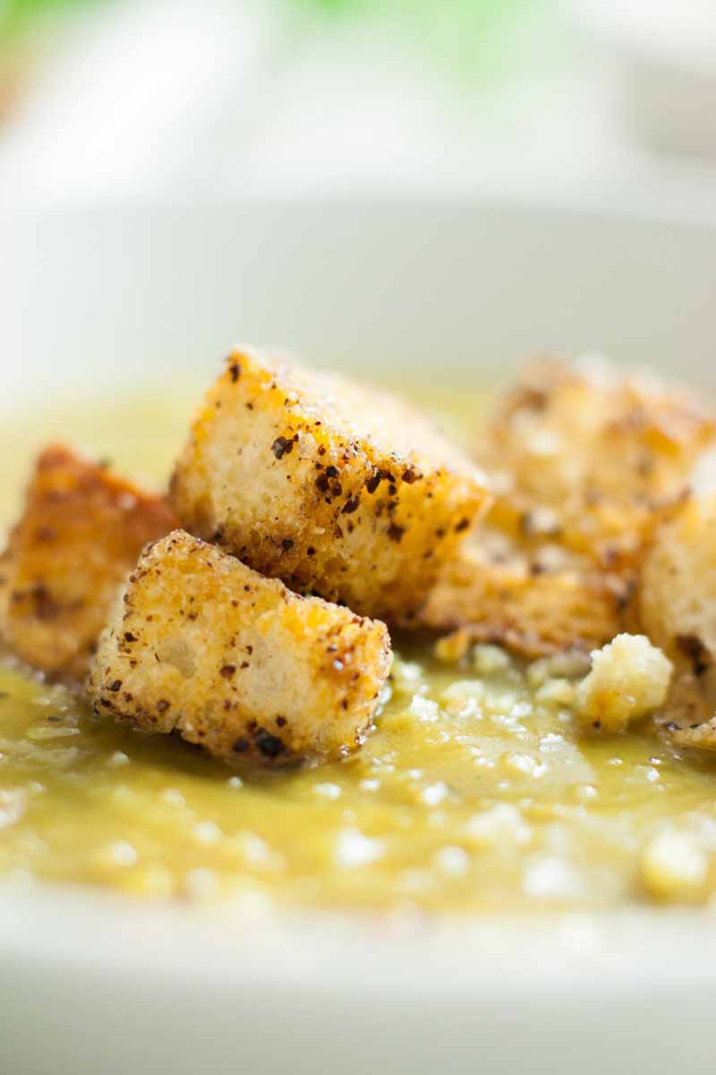A close up of a topping of sumac-spiced croutons on top of a vegan split pea soup.