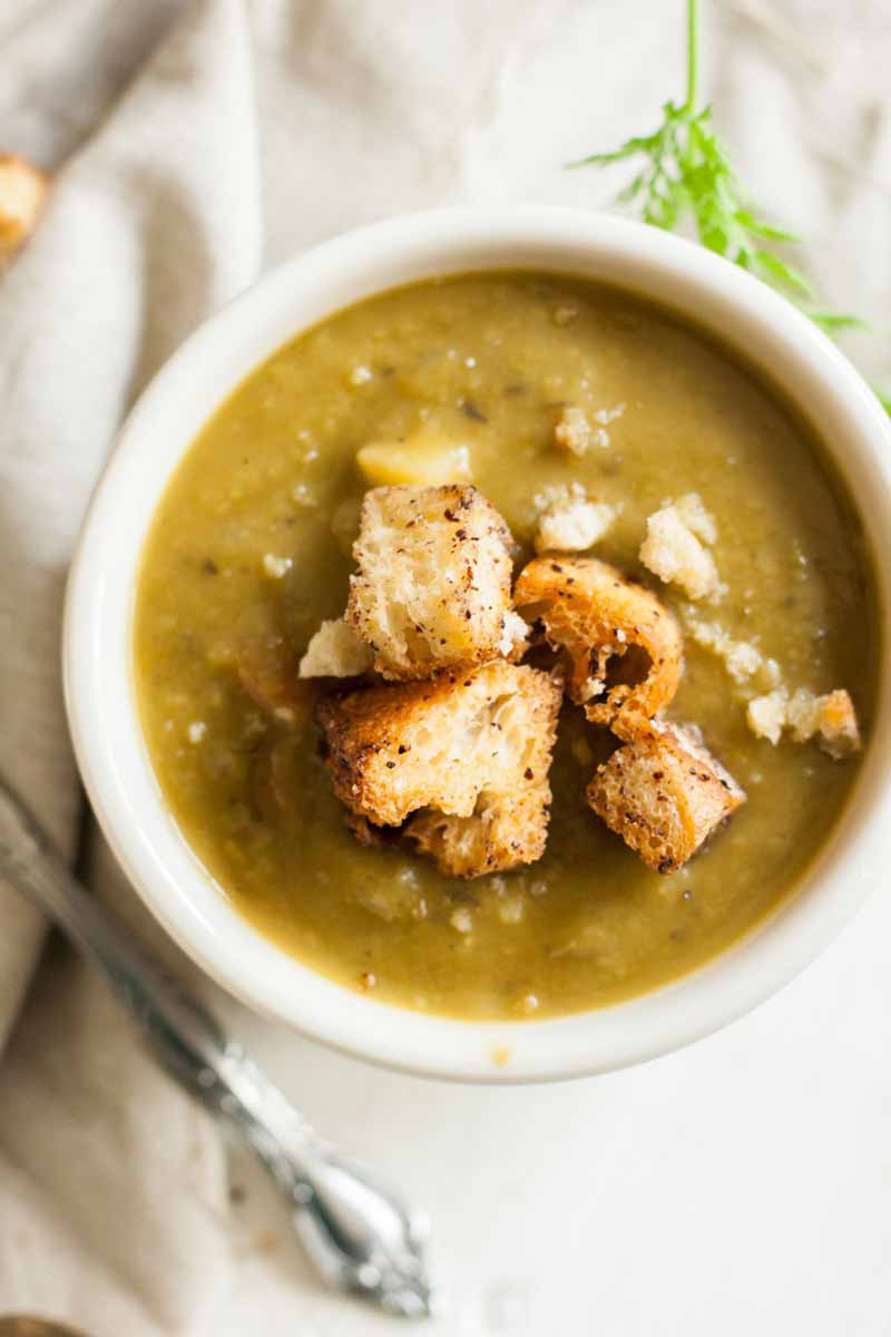 Top down view of a bowl vegan split pea soup topped with sumac-spiced croutons.