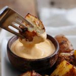 Horizontal image of a fork and potato dipped in aioli.