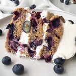 Horizontal image of a layered blueberry dessert with white frosting.