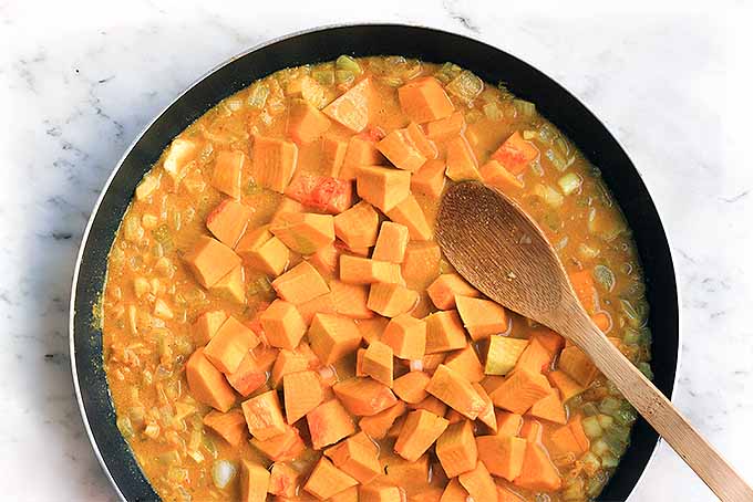 Cubed pumpkin added to the curry mixture in the skillet. Top down view.