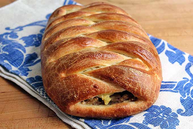 Braided filled brioche bread loaf on a blue and white tablecloth.