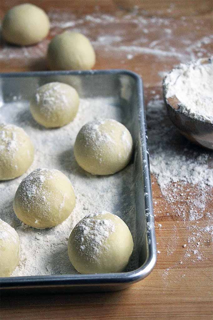 Balls of brioche dough in an aluminum baking pan.
