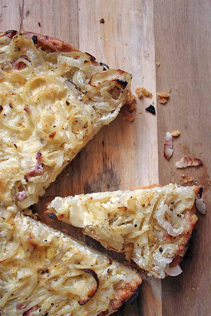 Close up and top view of a classic German onion tart with several slices removed.
