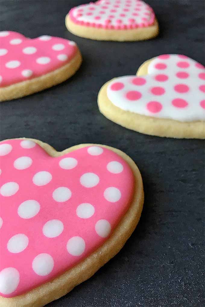 Learn how to make these adorable polka dot pink and white sugar cookie hearts for Valentine's Day. We'll teach you how! Just follow the link, or pin it for later: https://foodal.com/recipes/desserts/cookie-decorating-tips-valentines-day/