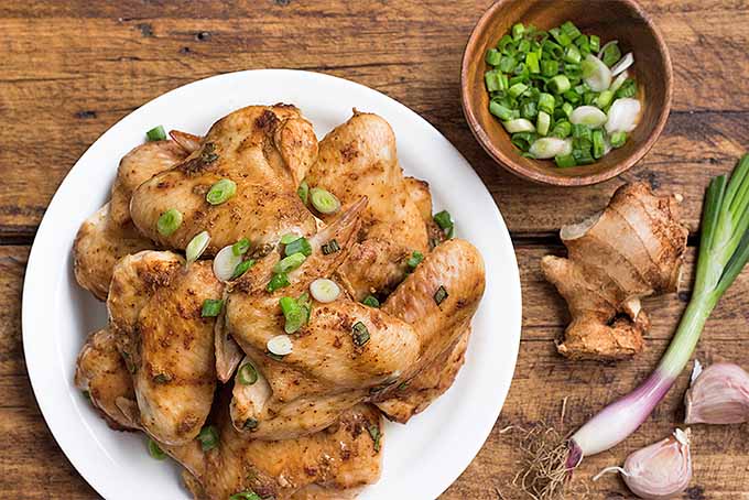 A plate of simple spicy chicken wings with scallions, ginger, and garlic. | Foodal.com