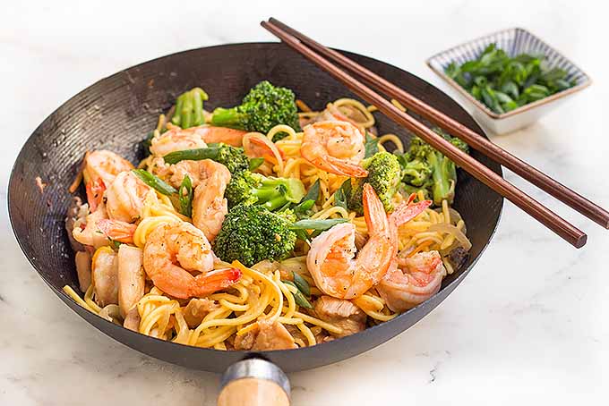 Enjoy a bowl of chicken and shrimp lo mein with assorted vegetables.